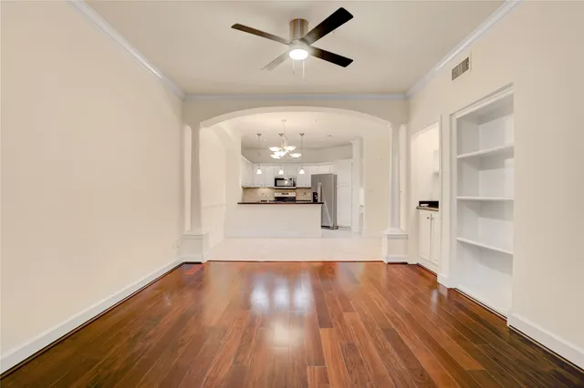 a view of a big room with wooden floor a ceiling fan and windows
