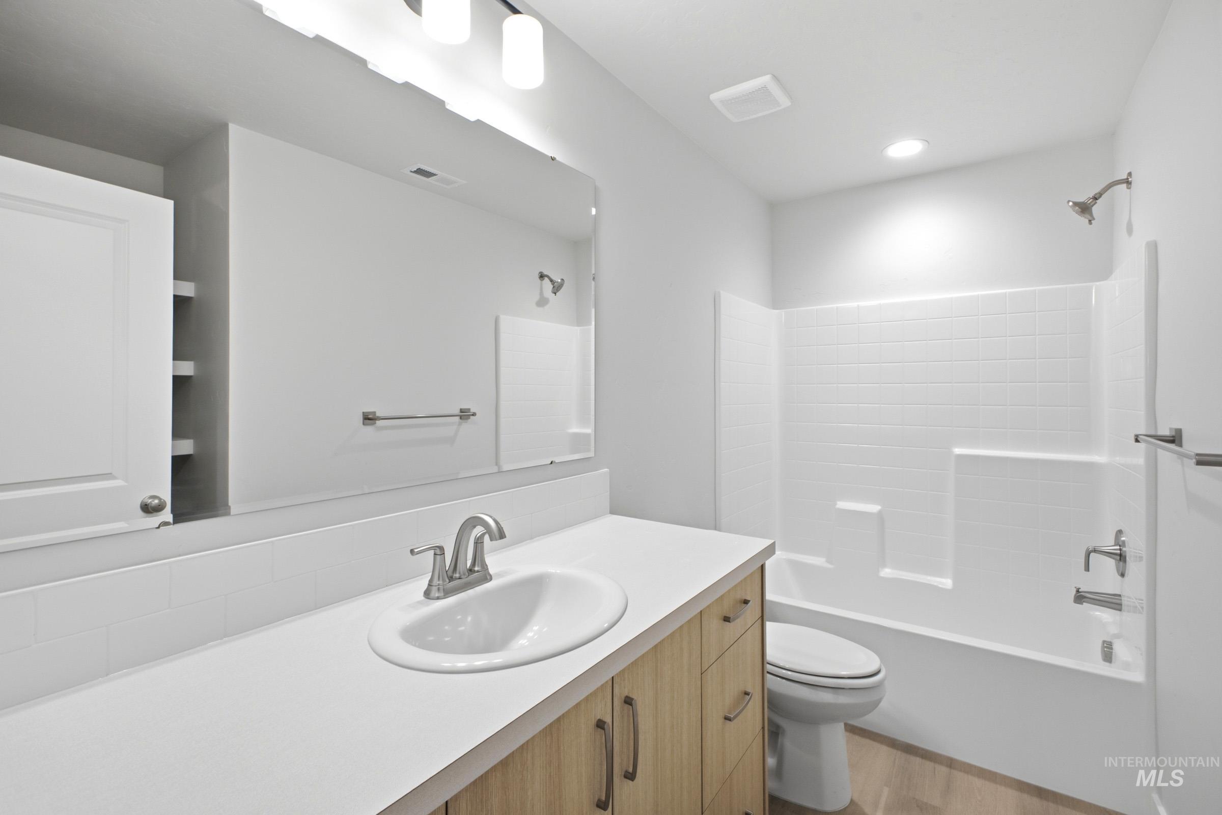13336 Bank Street Caldwell, ID 83607 - Photo 18 of 24 Vanity with wood-finish cabinetry and a white countertop, featuring an undermount sink and brushed nickel faucet