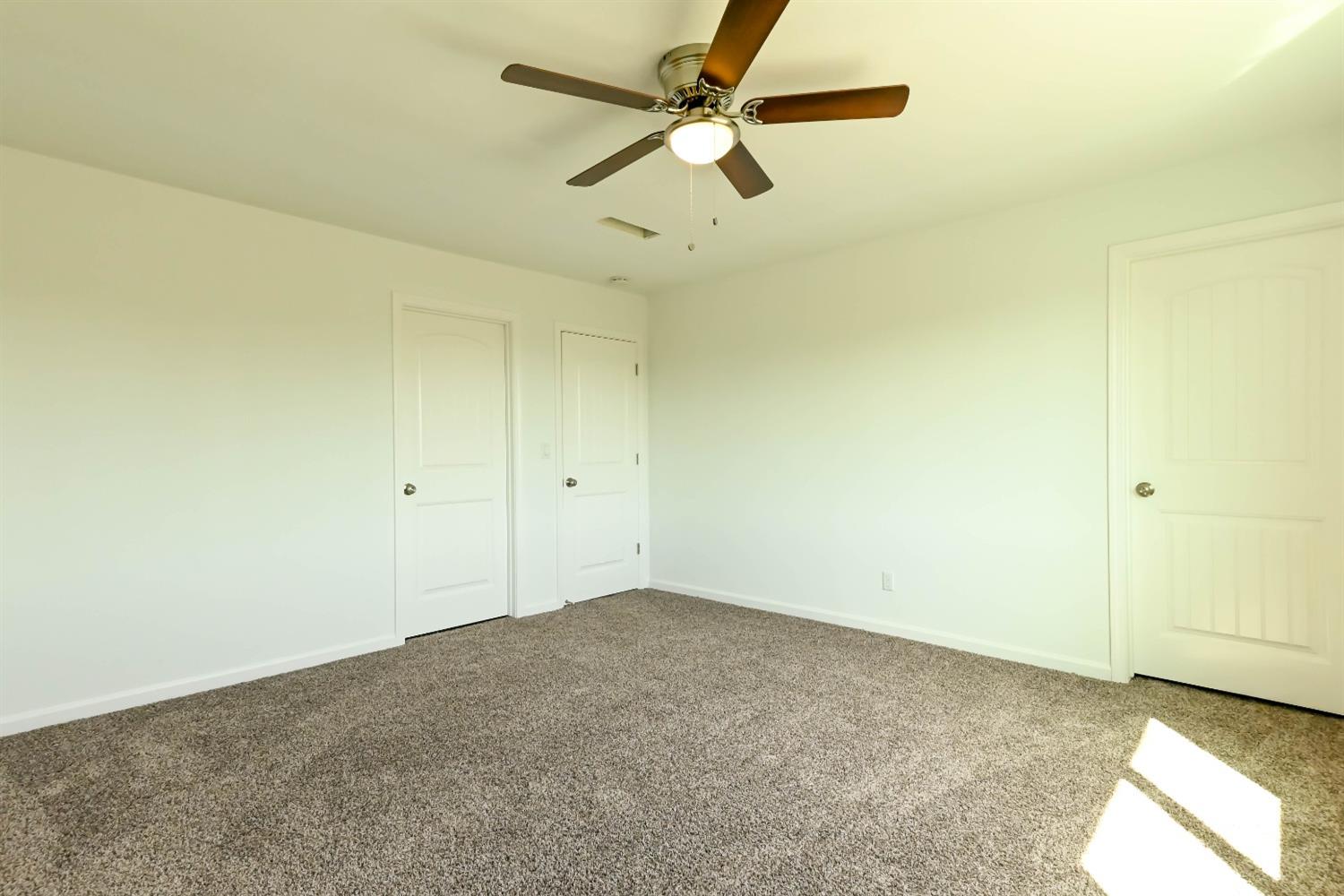 18071 Daley Road Madera, CA 93638 - Photo 12 of 25 an empty room with a ceiling fan and carpet