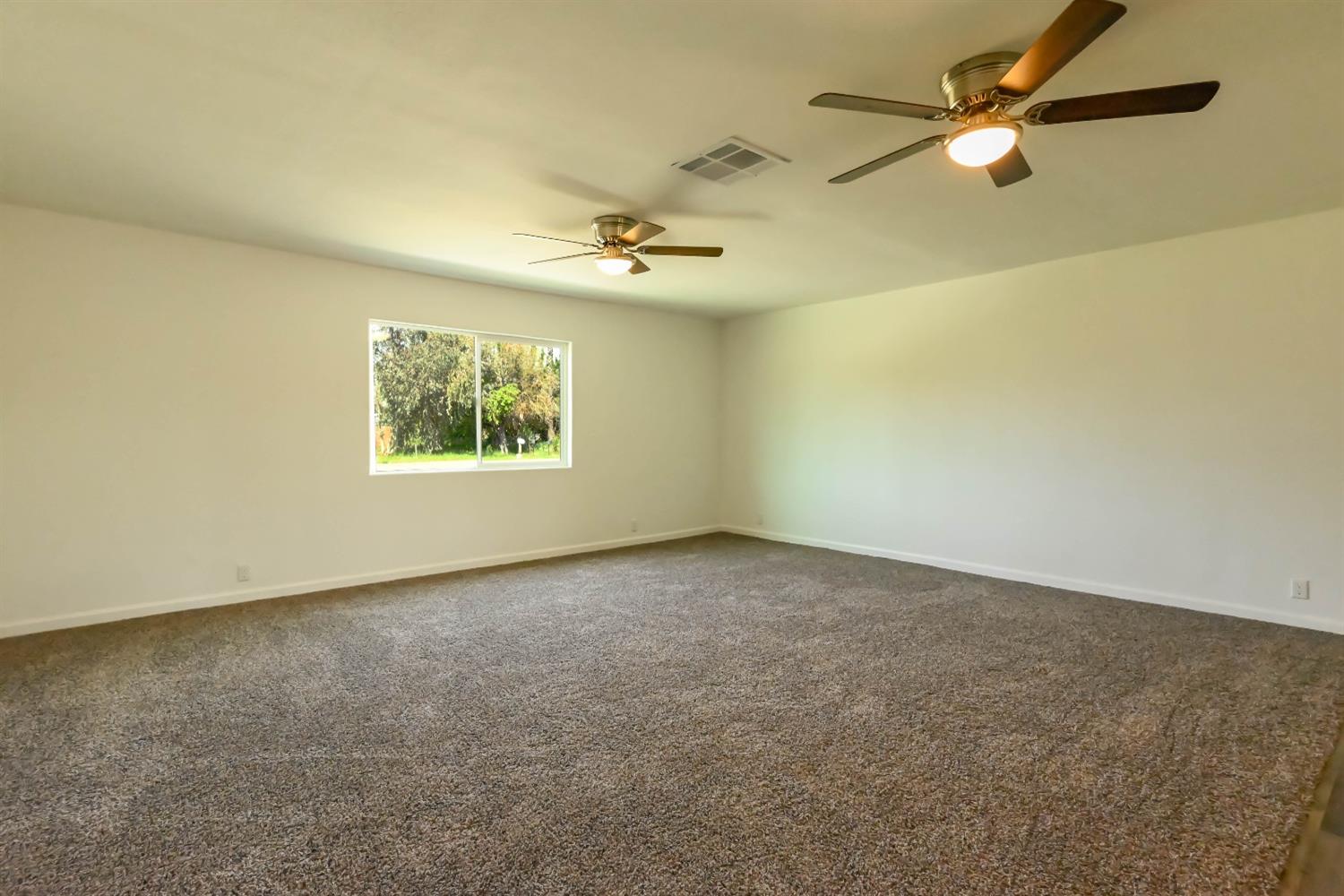 18071 Daley Road Madera, CA 93638 - Photo 5 of 25 an empty room with windows and fan