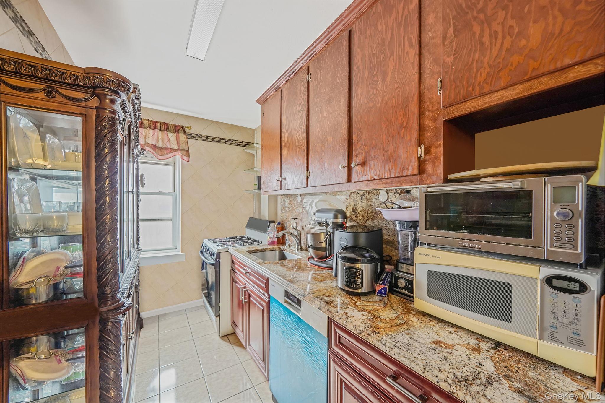 39-45 51st Street, Unit 5C Queens, NY 11377 - Photo 9 of 17 a kitchen with stainless steel appliances granite countertop a stove a sink and a microwave