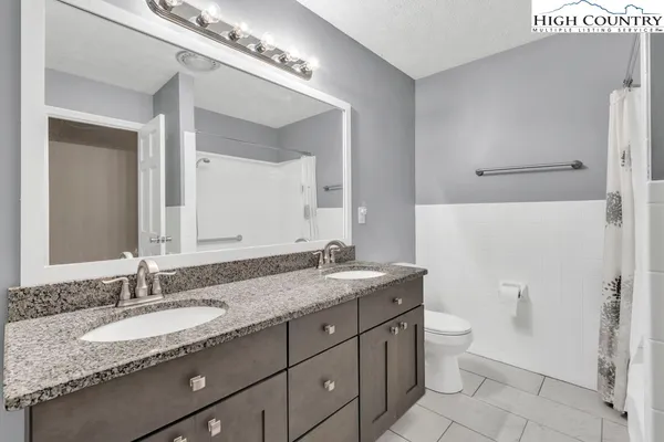 a bathroom with a granite countertop sink a toilet and a mirror