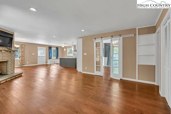 a view of an empty room with wooden floor and a fireplace