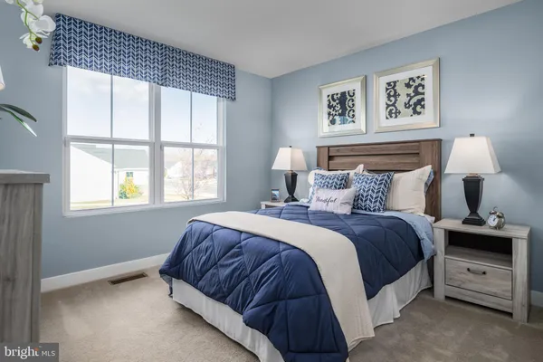 a bedroom with a bed and a lamp on dresser