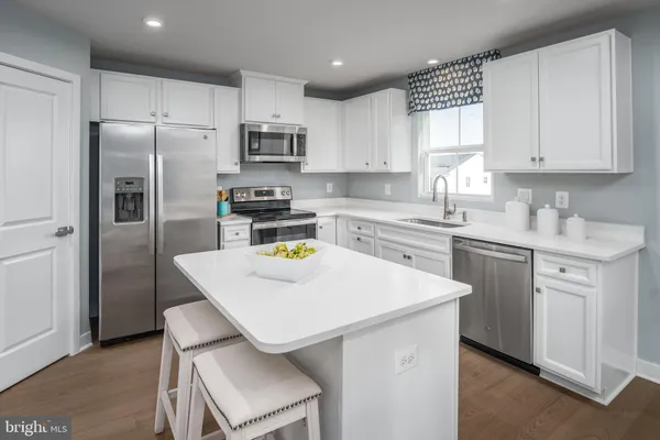 a kitchen with stainless steel appliances granite countertop a sink a stove a refrigerator a white table and chairs