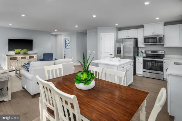 a living room with stainless steel appliances furniture a flat screen tv and a table