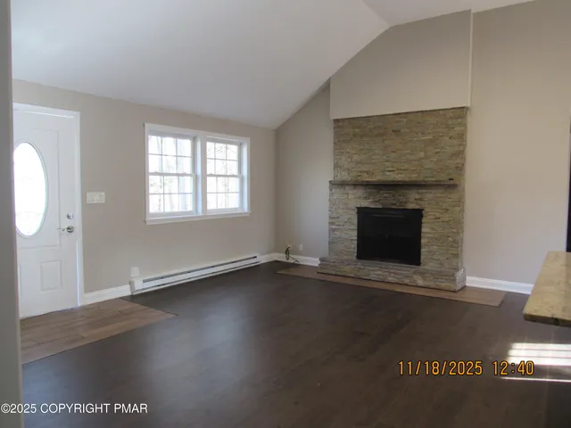 an empty room with wooden floor fireplace and windows