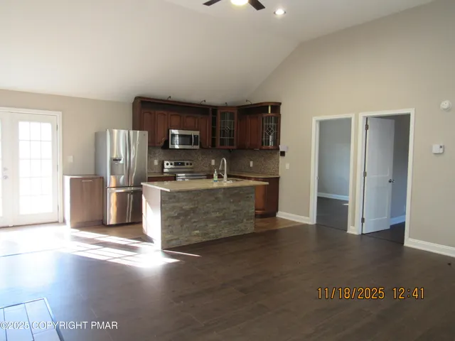 a living room with stainless steel appliances kitchen island granite countertop a refrigerator and a stove top oven