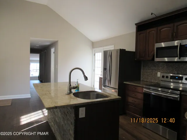 a kitchen with granite countertop a refrigerator and a stove top oven