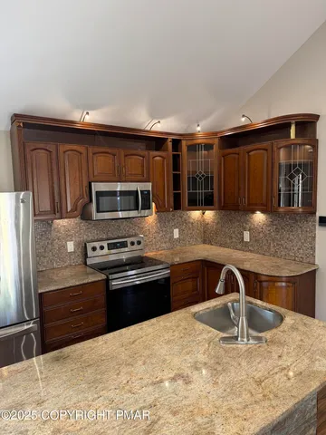 a kitchen with stainless steel appliances granite countertop a stove a sink and a microwave
