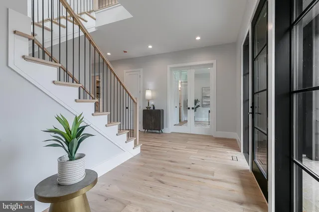 a hallway with wooden floor stairs and a potted plant