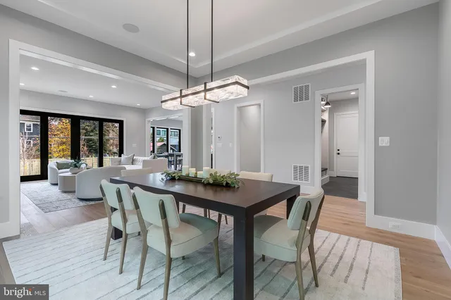 a dining room with wooden floor a chandelier a wooden table and chairs