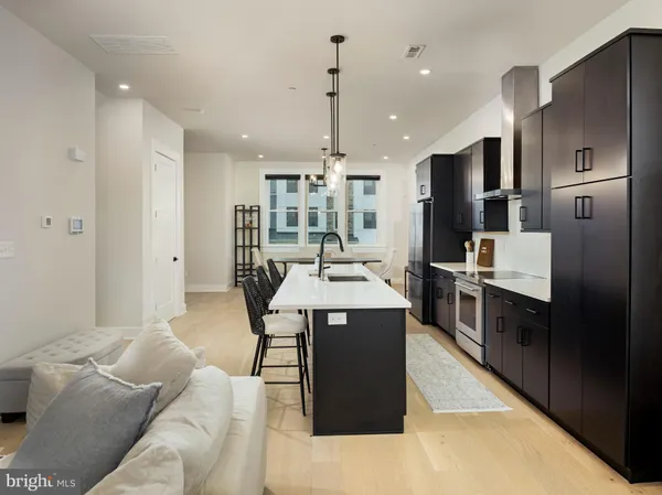 a kitchen with stainless steel appliances kitchen island granite countertop a refrigerator a stove and a sink with wooden floor