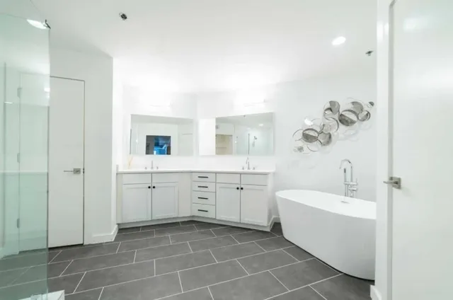 a bathroom with a double vanity sink a mirror and a bathtub