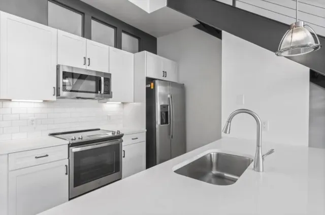 a kitchen with granite countertop a sink stainless steel appliances and cabinets