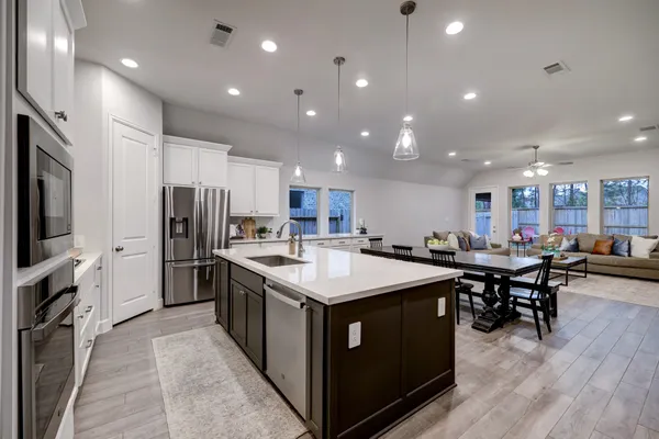 a large kitchen with kitchen island a sink a center island stainless steel appliances a dining table and chairs