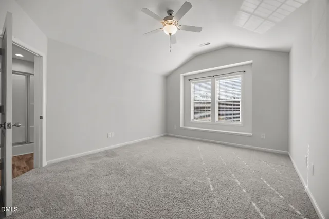 an empty room with chandelier fan and windows
