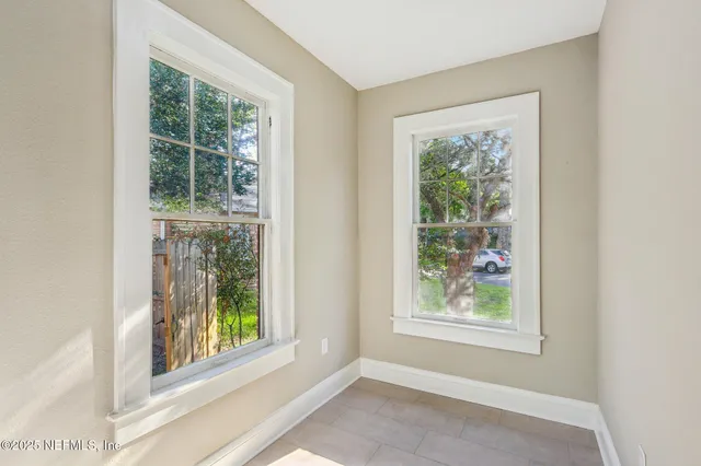 a view of an empty room with a window and wooden floor