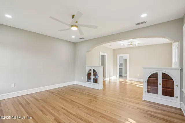 a view of an empty room with window and wooden floor