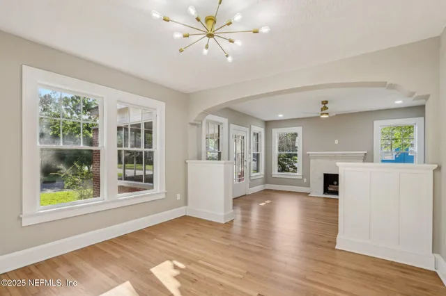 a view of an empty room with window and wooden floor