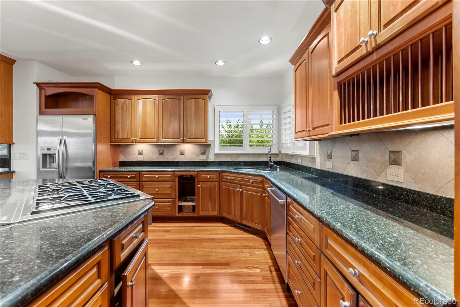 14046 Lexington Circle Westminster, CO 80023 - Photo 18 of 40 a kitchen with stainless steel appliances granite countertop a stove a sink dishwasher and cabinets with wooden floor