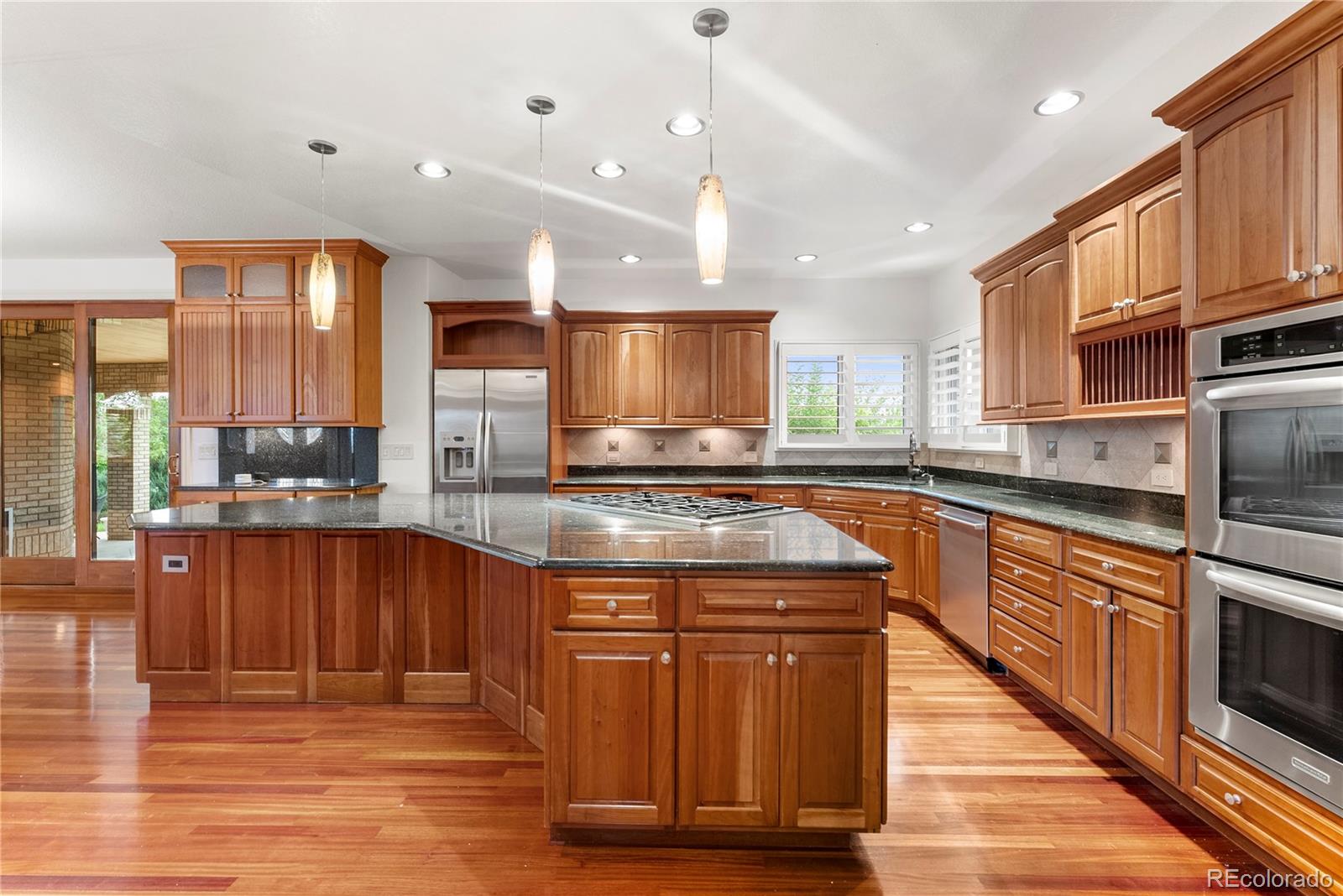 14046 Lexington Circle Westminster, CO 80023 - Photo 7 of 40 a kitchen with stainless steel appliances granite countertop a stove a sink dishwasher and a microwave oven with large wooden cabinets
