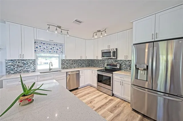a kitchen with white cabinets and chandelier