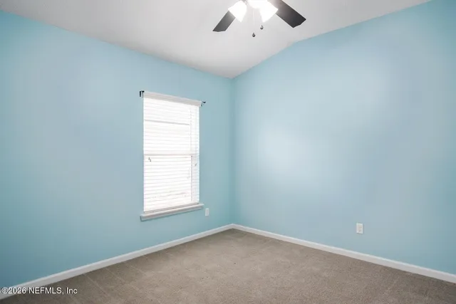 an empty room with a window and a ceiling fan