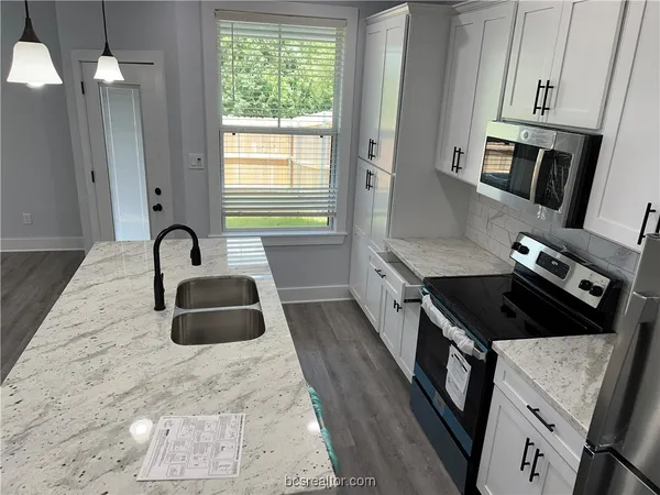 a kitchen with granite countertop a stove a sink and a refrigerator