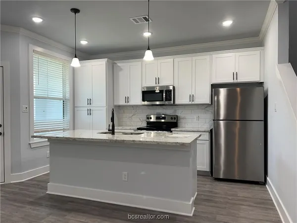a kitchen with kitchen island a white counter top space cabinets and stainless steel appliances