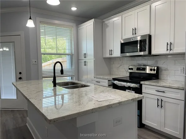 a kitchen with stainless steel appliances granite countertop a sink a stove and cabinets