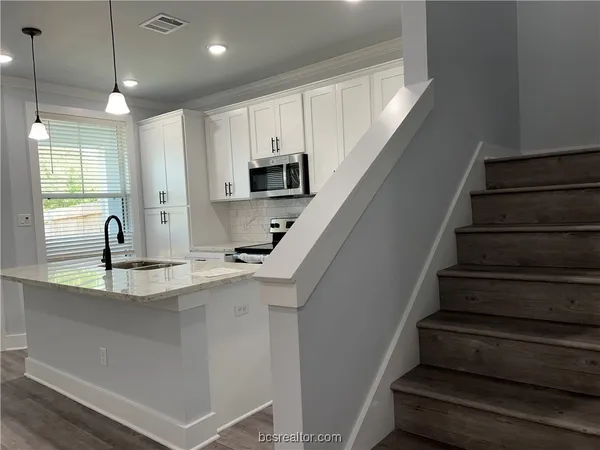 a kitchen with kitchen island granite countertop a sink stainless steel appliances and cabinets