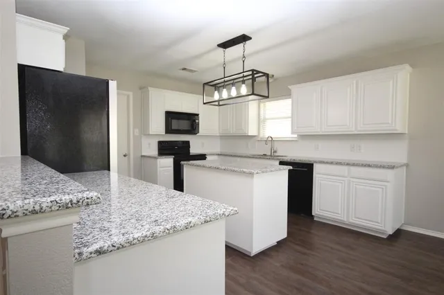 a kitchen with kitchen island granite countertop stainless steel appliances a sink stove and refrigerator
