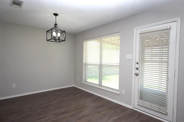 a view of empty room with wooden floor and window