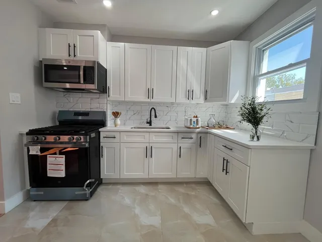 a kitchen with stainless steel appliances granite countertop a sink a stove a microwave and wooden cabinets