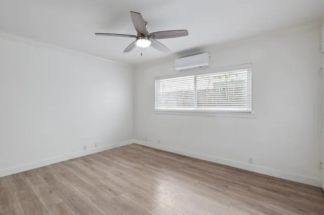 an empty room with wooden floor fan and windows
