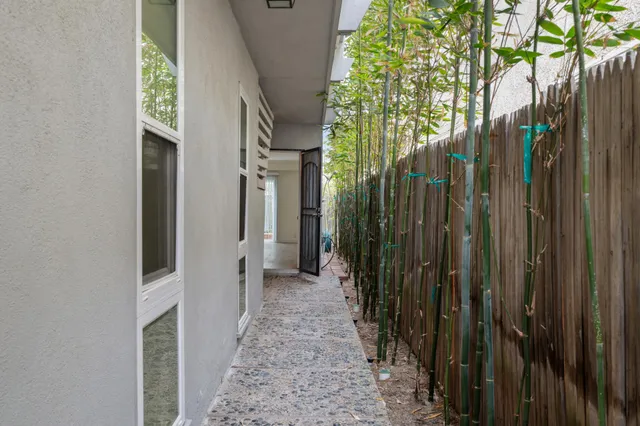 a view of a pathway of a house with a yard and wooden fence