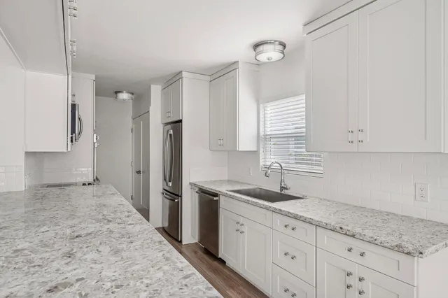 a kitchen with granite countertop white cabinets and stainless steel appliances