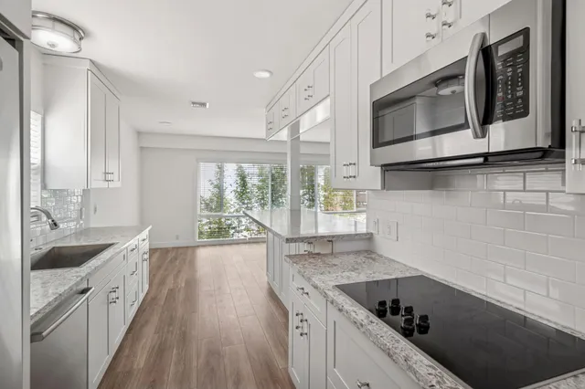a kitchen with granite countertop a sink and steel appliances