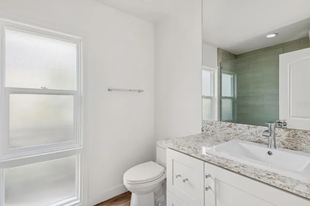 a bathroom with a granite countertop sink a toilet and a mirror