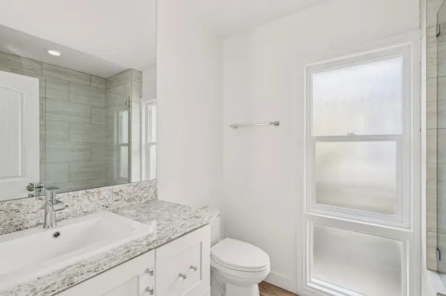 a bathroom with a granite countertop sink toilet and shower