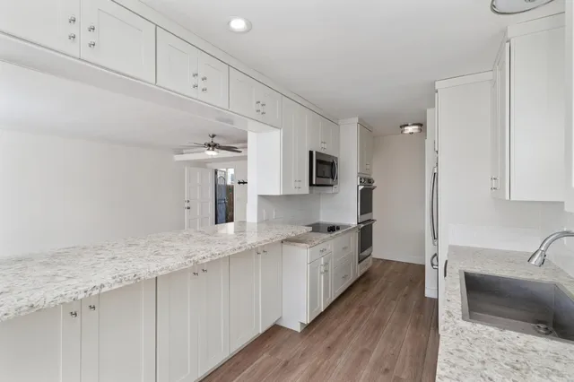 a kitchen with granite countertop a sink stainless steel appliances and cabinets