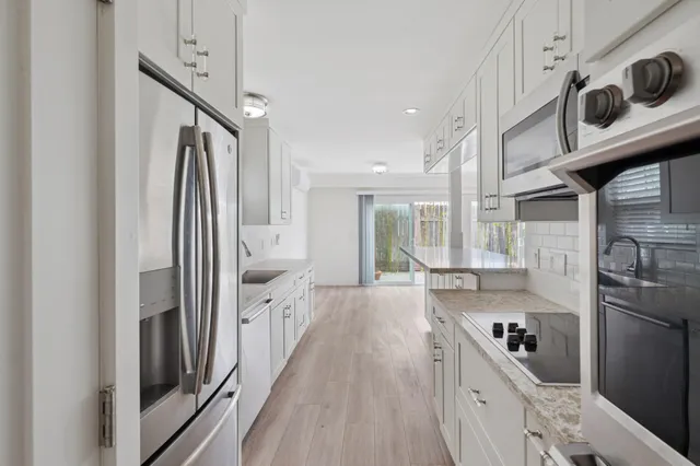 a kitchen with stainless steel appliances granite countertop a refrigerator a stove and a sink with wooden floor