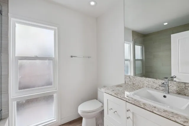 a bathroom with a granite countertop sink a toilet and a mirror