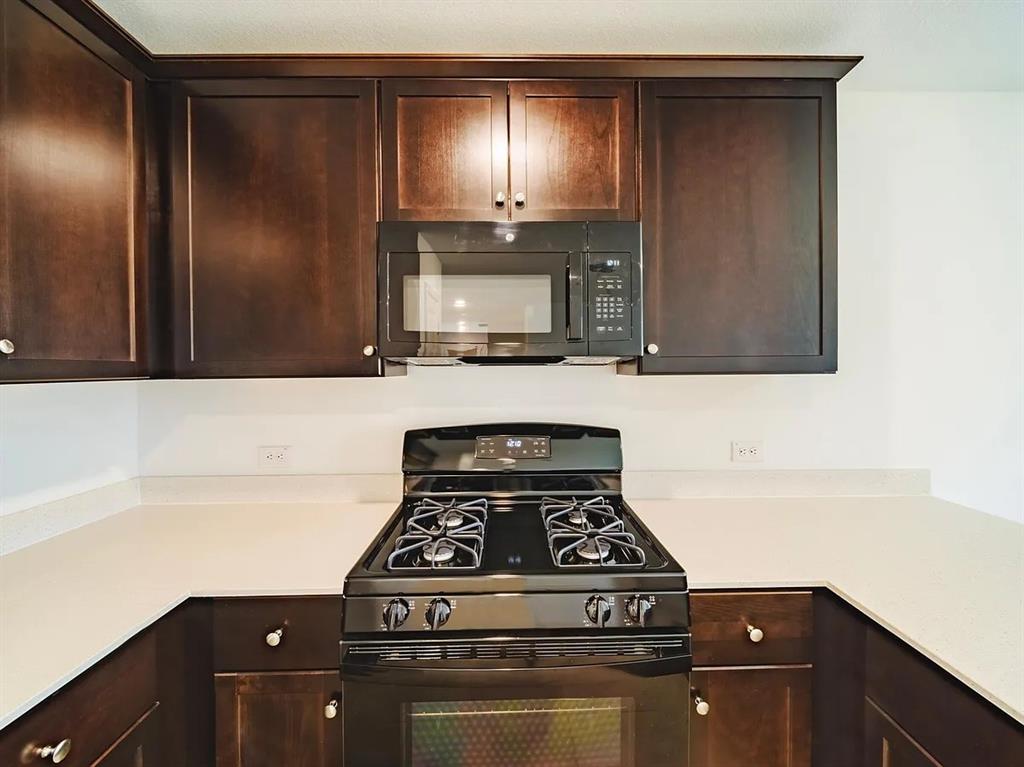 352 Sun Bluff Road Fort Worth, TX 76052 - Photo 5 of 33 Kitchen featuring dark wood-finish cabinetry, light countertops, black gas range, and an over-the-range microwave