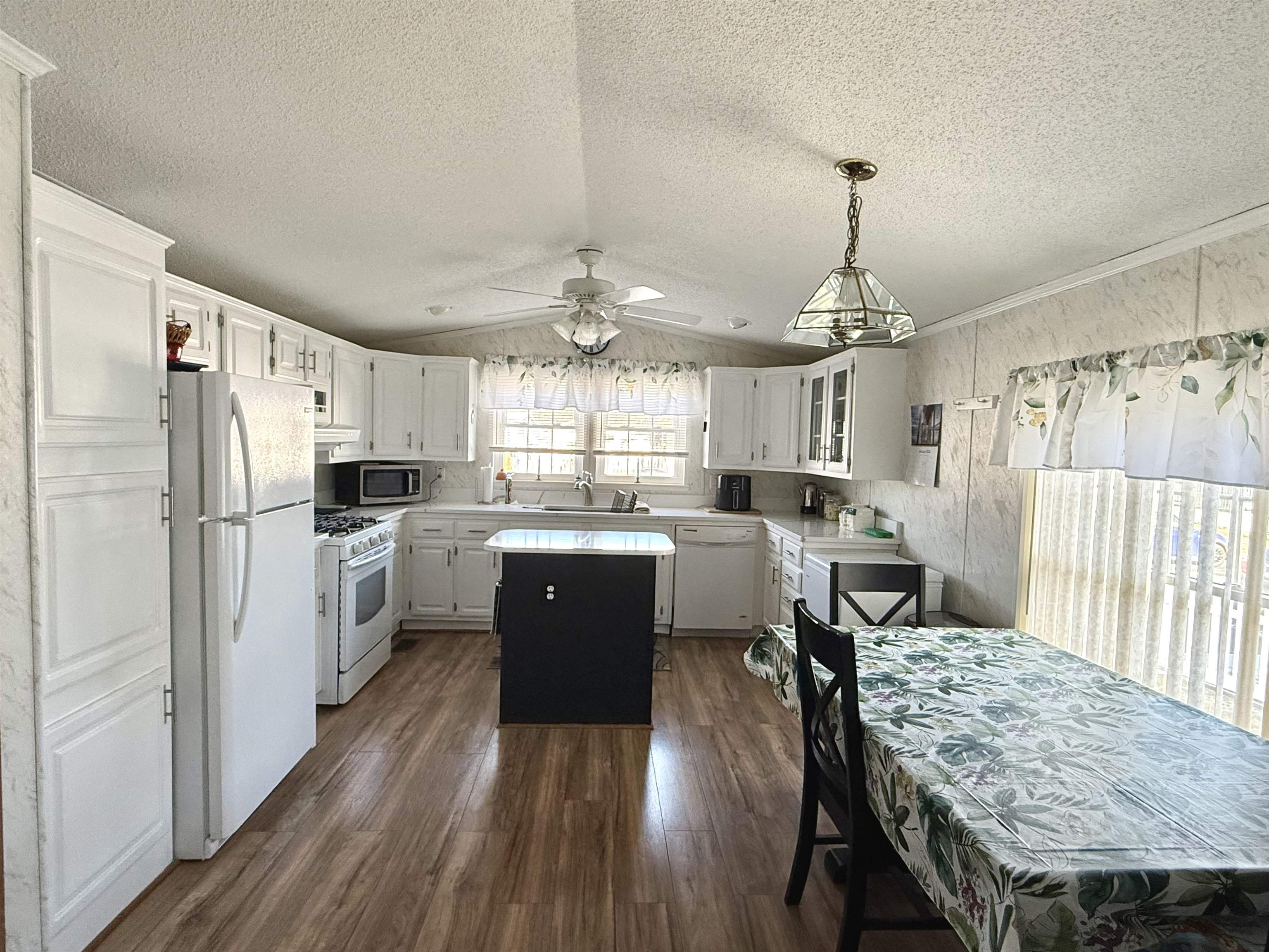 68 Priest Boulevard Rio Grande, NJ 08242 - Photo 7 of 28 a kitchen with refrigerator a sink dishwasher a dining table and chairs with wooden floor