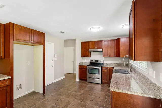 a large kitchen with stainless steel appliances granite countertop a stove a sink and a refrigerator