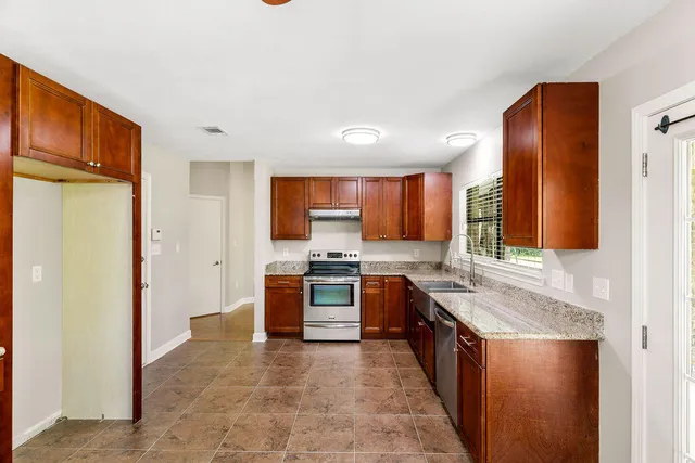 a large kitchen with stainless steel appliances granite countertop a stove a sink and a refrigerator
