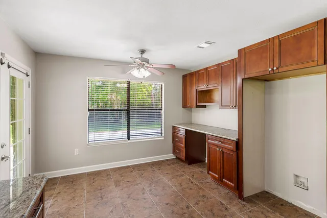 a view of an empty room with a window and kitchen view