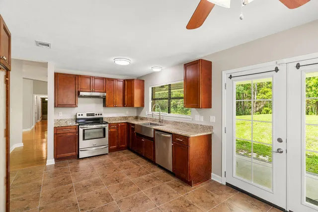 a large kitchen with stainless steel appliances granite countertop a stove a sink and a refrigerator